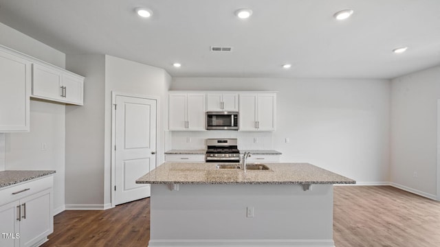 kitchen featuring stainless steel appliances, white cabinetry, sink, and a center island with sink