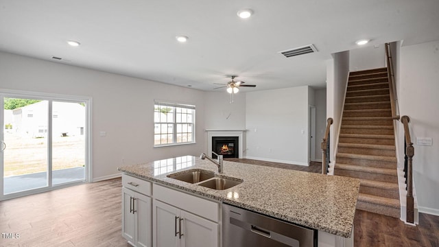 kitchen with sink, dishwasher, an island with sink, hardwood / wood-style flooring, and white cabinets