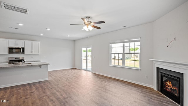 unfurnished living room with sink, wood-type flooring, and ceiling fan