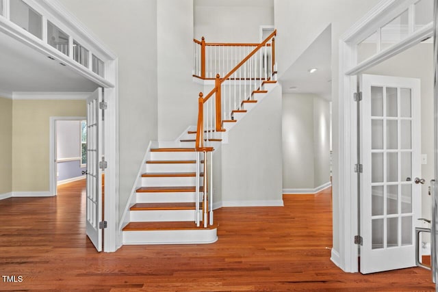 staircase featuring crown molding, baseboards, and wood finished floors