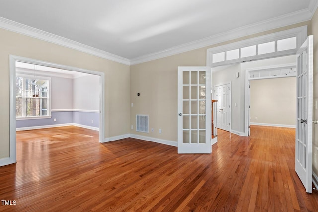 empty room with wood-type flooring, visible vents, crown molding, and french doors