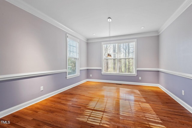 empty room featuring crown molding, baseboards, and wood finished floors