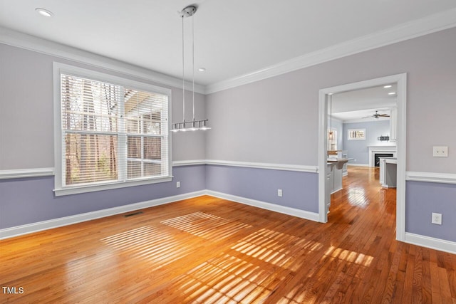 spare room featuring baseboards, visible vents, ornamental molding, and hardwood / wood-style floors