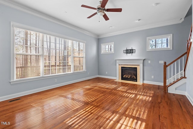 unfurnished living room featuring plenty of natural light, visible vents, crown molding, and stairway