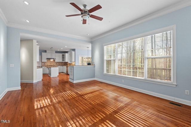 unfurnished living room with ornamental molding, visible vents, and baseboards