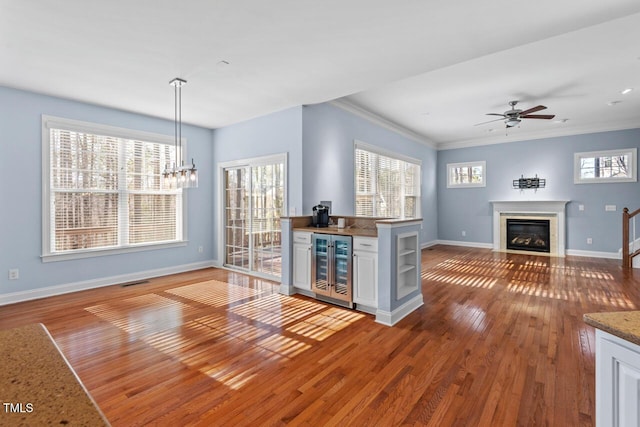 kitchen featuring baseboards, hardwood / wood-style flooring, a fireplace with flush hearth, wine cooler, and open floor plan