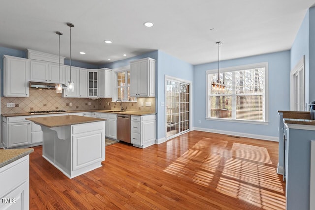 kitchen featuring tasteful backsplash, stainless steel dishwasher, white cabinets, light wood-type flooring, and under cabinet range hood