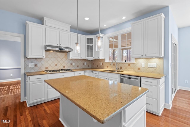 kitchen with stainless steel appliances, white cabinetry, a sink, and under cabinet range hood