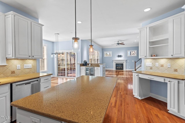 kitchen featuring ceiling fan, white cabinets, wood finished floors, and a glass covered fireplace