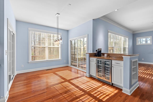 bar with beverage cooler, visible vents, baseboards, hardwood / wood-style floors, and crown molding