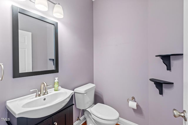 bathroom with baseboards, vanity, and toilet