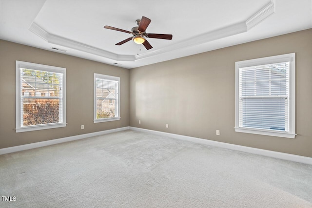 spare room with baseboards, a raised ceiling, and light colored carpet