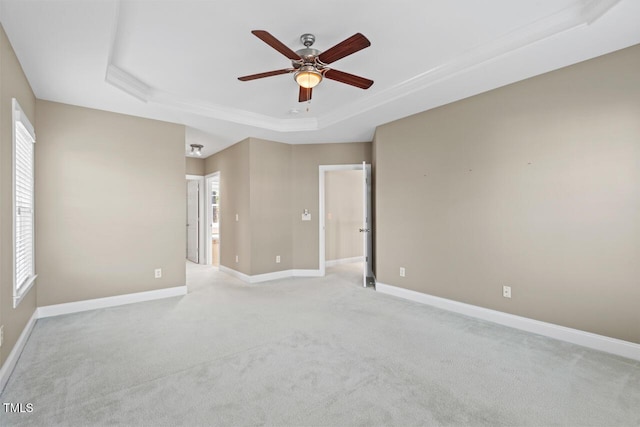 unfurnished room with light carpet, baseboards, a tray ceiling, and ceiling fan