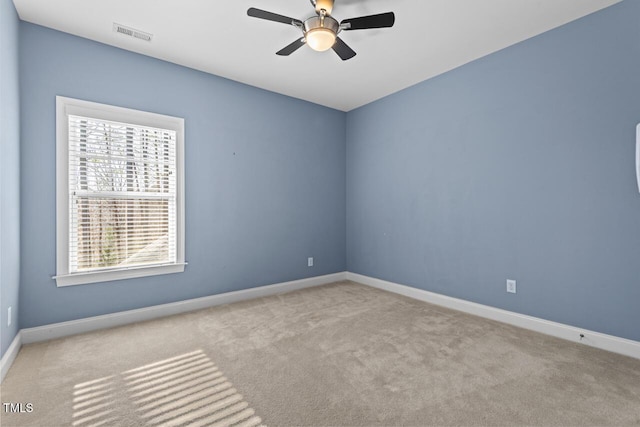 empty room with ceiling fan, carpet flooring, visible vents, and baseboards