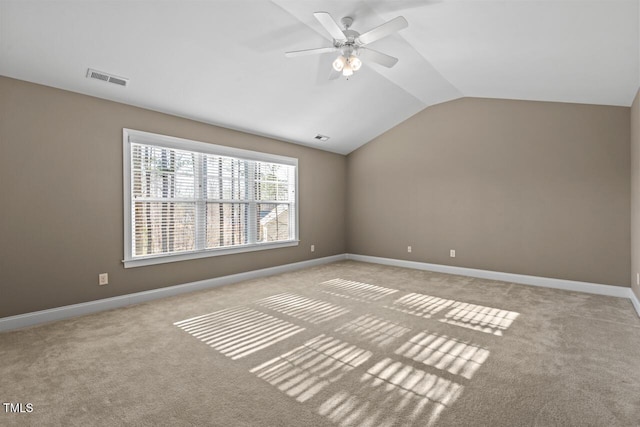 empty room with vaulted ceiling, carpet, visible vents, and baseboards