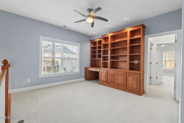 unfurnished office featuring light carpet, built in study area, plenty of natural light, and visible vents