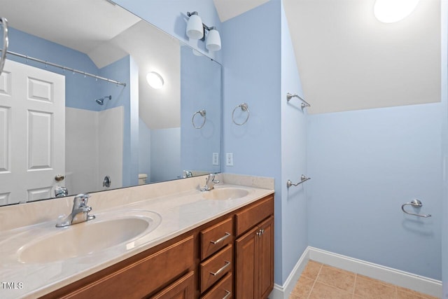 bathroom featuring tile patterned floors, a sink, baseboards, and double vanity