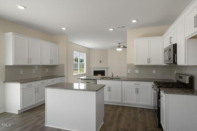 kitchen featuring white cabinetry, stainless steel appliances, kitchen peninsula, and sink