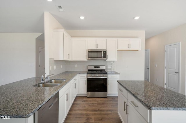 kitchen with sink, dark stone counters, stainless steel appliances, decorative backsplash, and white cabinets