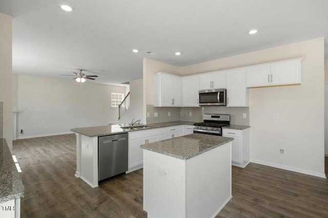 kitchen featuring stainless steel appliances, light stone countertops, a kitchen island, and white cabinets