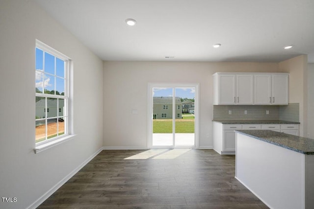 kitchen featuring white cabinetry, decorative backsplash, dark hardwood / wood-style floors, and dark stone countertops