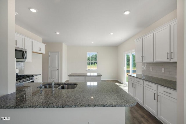 kitchen featuring appliances with stainless steel finishes, sink, dark stone counters, and white cabinets