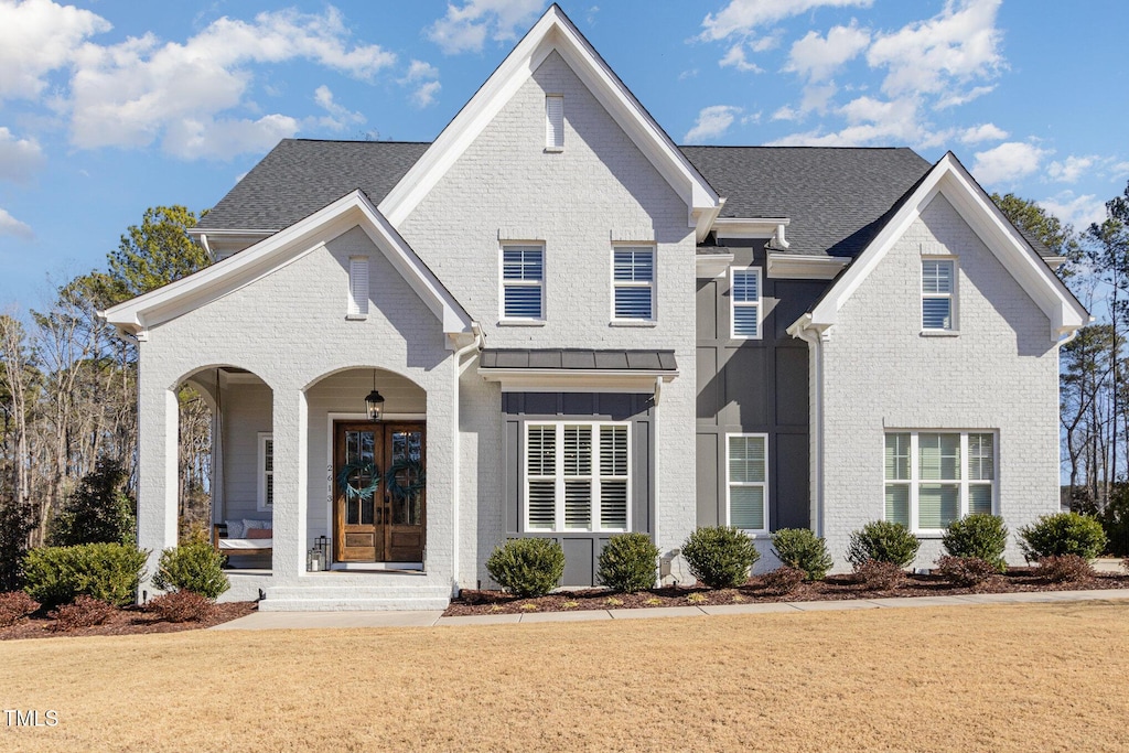 view of front of property with french doors, covered porch, and a front yard