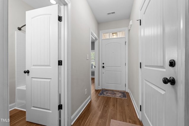 doorway to outside with wood finished floors, visible vents, and baseboards