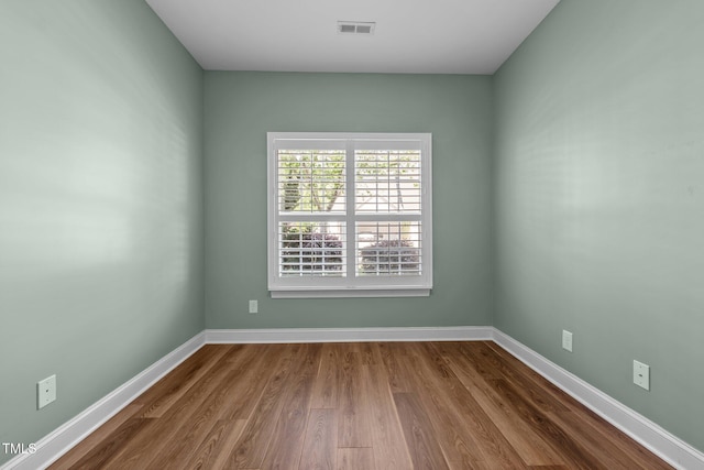 spare room with baseboards, visible vents, and dark wood finished floors