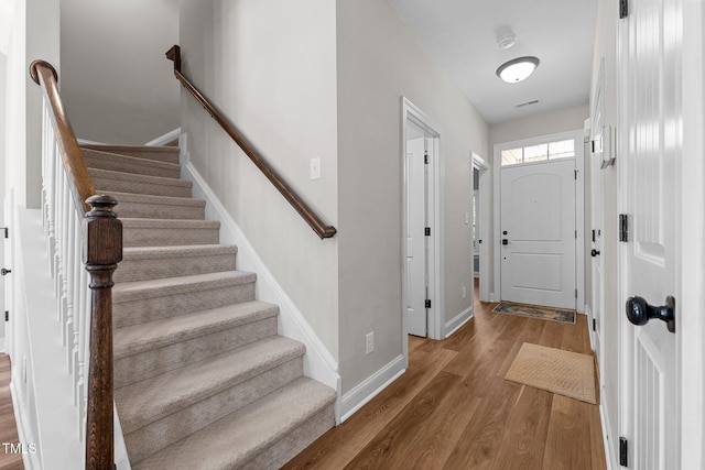 entryway with baseboards, wood finished floors, and stairs