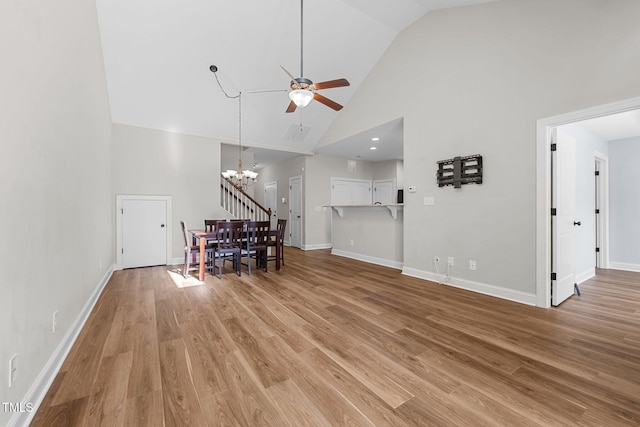 living room with high vaulted ceiling, baseboards, light wood-style flooring, and ceiling fan with notable chandelier