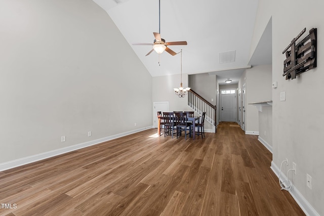 interior space with ceiling fan with notable chandelier, baseboards, wood finished floors, and high vaulted ceiling