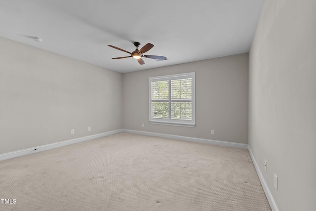 spare room featuring baseboards, ceiling fan, and light colored carpet