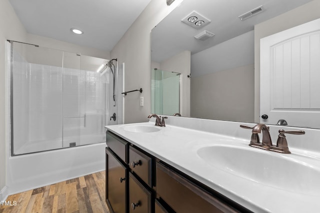 bathroom featuring enclosed tub / shower combo, wood finished floors, a sink, and visible vents