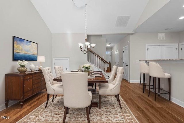 dining space with vaulted ceiling, wood finished floors, baseboards, and an inviting chandelier
