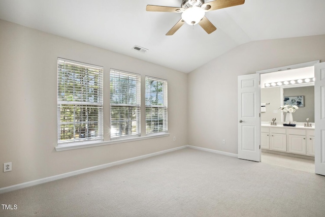 unfurnished bedroom with visible vents, light carpet, a sink, vaulted ceiling, and baseboards