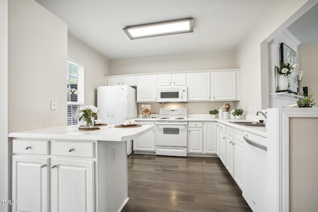 kitchen with white appliances, white cabinets, a peninsula, light countertops, and a sink