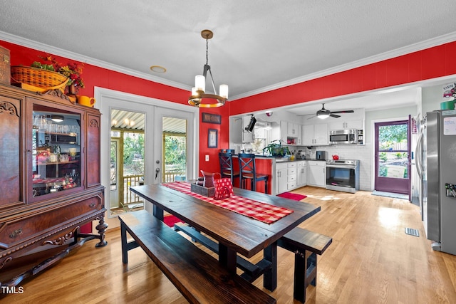 dining space featuring french doors, crown molding, visible vents, light wood-style floors, and a textured ceiling