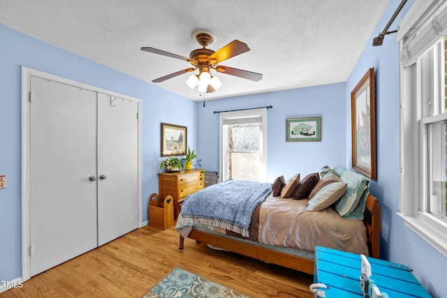 bedroom featuring a ceiling fan, a closet, a textured ceiling, and light wood finished floors