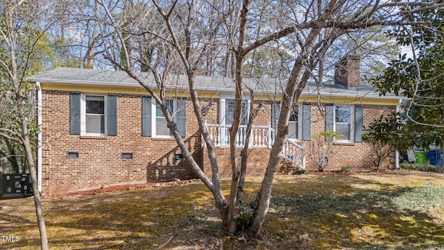 view of front of house with crawl space, a front yard, a chimney, and brick siding