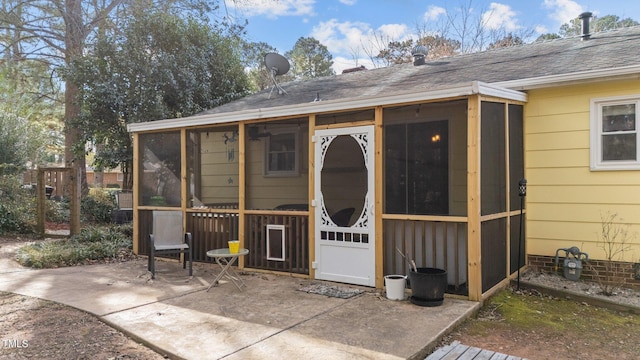 doorway to property featuring a patio and a shingled roof