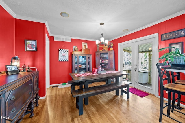 dining area with visible vents, french doors, a textured ceiling, crown molding, and light wood-type flooring