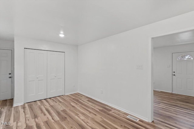 unfurnished room featuring light wood-type flooring and a closet