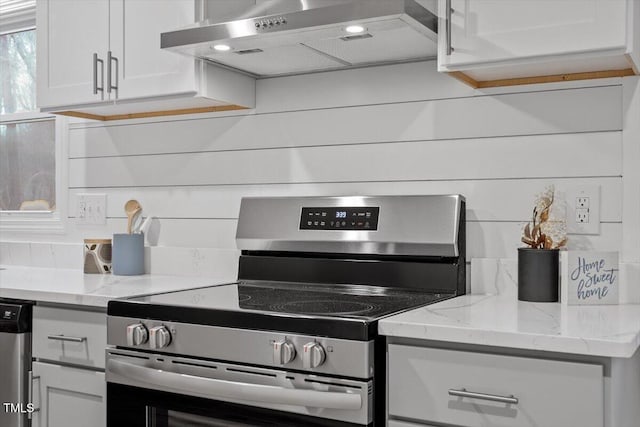 kitchen with appliances with stainless steel finishes, wall chimney exhaust hood, white cabinetry, and light stone counters