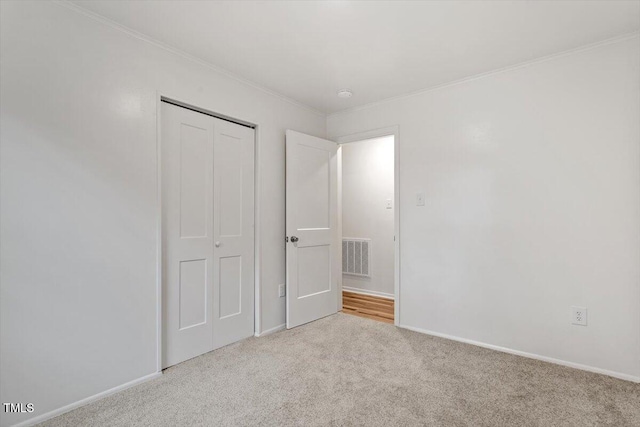 unfurnished bedroom featuring ornamental molding, a closet, and light colored carpet