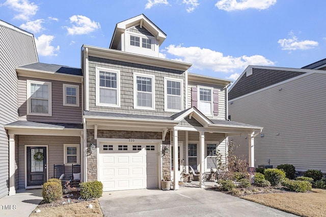 multi unit property with stone siding, covered porch, a garage, and concrete driveway