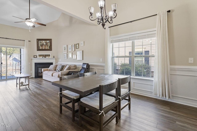 dining space featuring dark wood-style floors, a glass covered fireplace, wainscoting, and a decorative wall