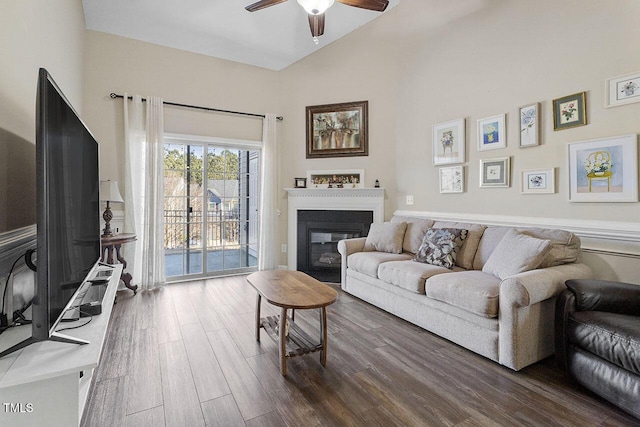 living area featuring high vaulted ceiling, dark wood finished floors, a ceiling fan, and a glass covered fireplace