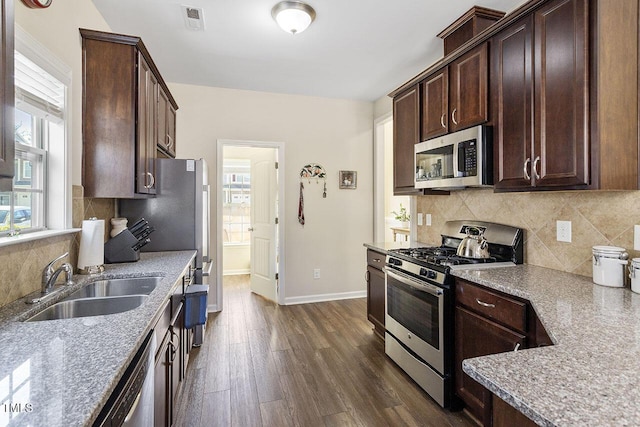 kitchen featuring a sink, visible vents, dark brown cabinets, appliances with stainless steel finishes, and dark wood-style floors