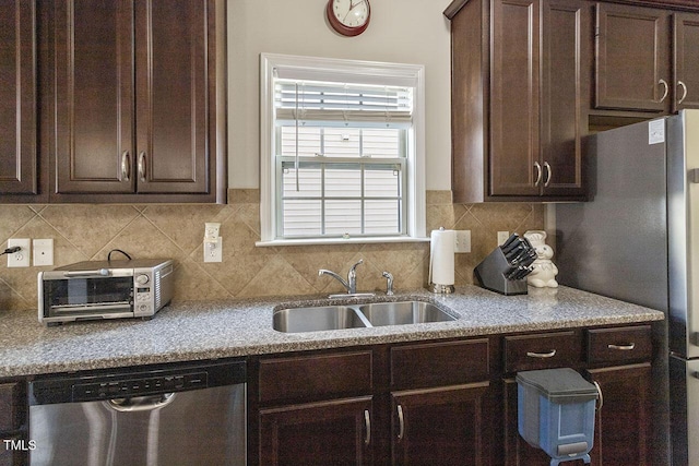 kitchen featuring a toaster, a sink, dark brown cabinets, appliances with stainless steel finishes, and backsplash